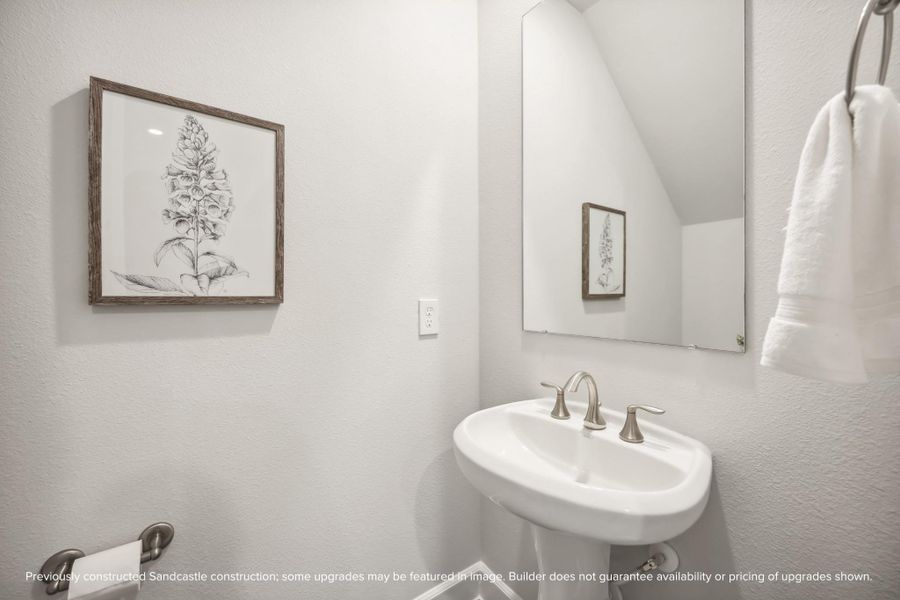 Nestled under the stairs, this powder room features a timeless pedestal sink, combining convenience and classic style.