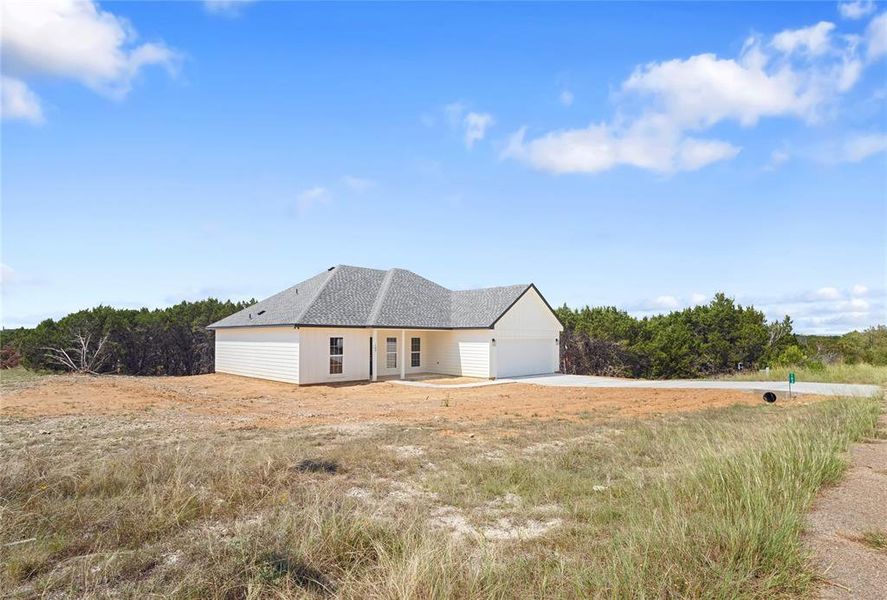 View of front of home with roof with shingles and a patio area