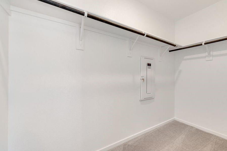 Walk in closet with electric panel and light colored carpet