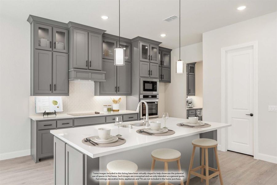 Kitchen with gray cabinets, white quartz island with seating, pendant lights, and stainless steel appliances