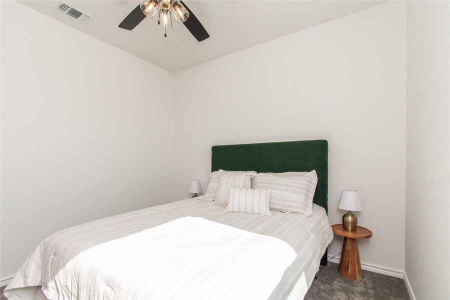 Carpeted bedroom with ceiling fan and baseboards