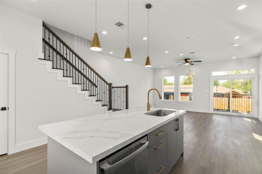 Bright modern kitchen featuring a large island with quartz countertops, sleek cabinetry, and gold accents. Bright modern kitchen featuring a large island with quartz countertops, sleek cabinetry, and gold accents.