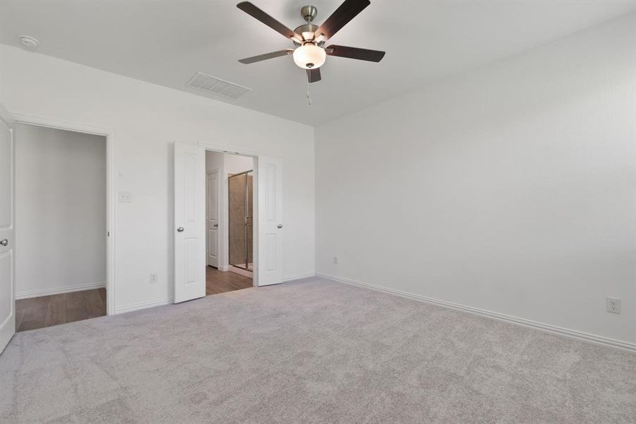 Unfurnished bedroom with ceiling fan and dark colored carpet