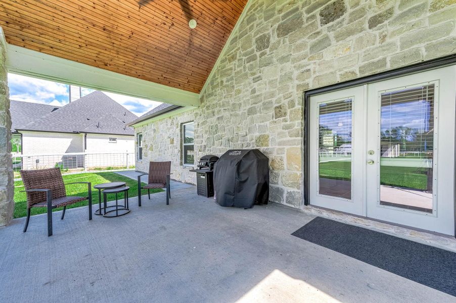 Another angle of the covered patio showcases the inviting outdoor seating area, stone exterior accents, and spacious setup ideal for entertaining or relaxing while enjoying views of the backyard.
