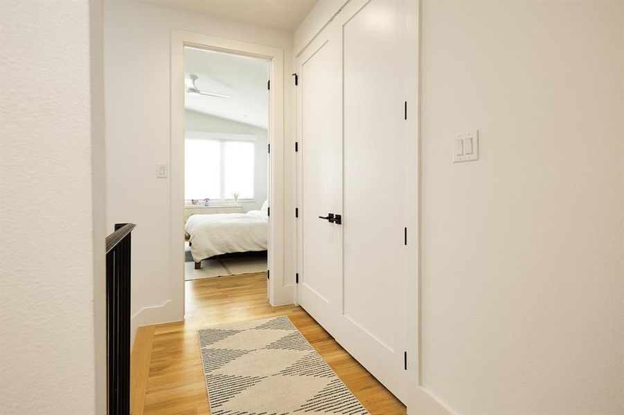 Corridor with laundry closest leading into primary bedroom