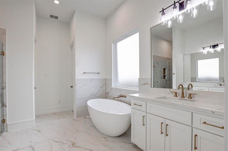 Bathroom featuring vanity, tile patterned flooring, a bathing tub, and tile walls