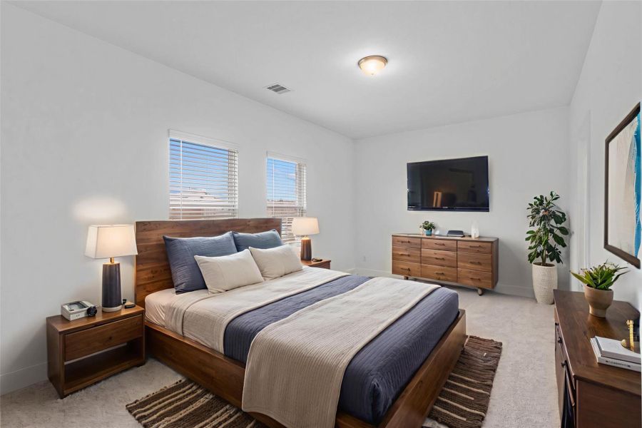 Spacious primary bedroom retreat with plush carpet, rear-facing windows for peaceful backyard views, and abundant natural light—designed for rest and relaxation. *Virtually Staged*