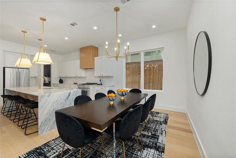 The dining area features light-toned flooring, a chandelier, and a window providing natural light