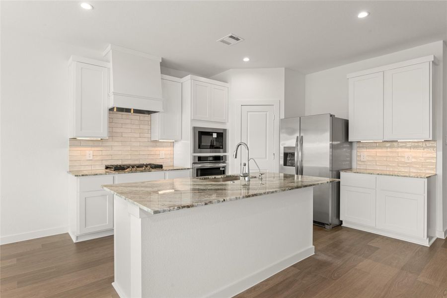 Step into this immaculate gourmet kitchen, featuring modern white cabinetry, sleek stainless steel appliances, and a beautiful subway tile backsplash. The oversized granite island provides ample space for meal prep and gathering, making it the true heart of the home. *Virtually Staged