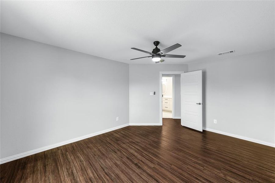 Empty room with dark wood finished floors and a ceiling fan