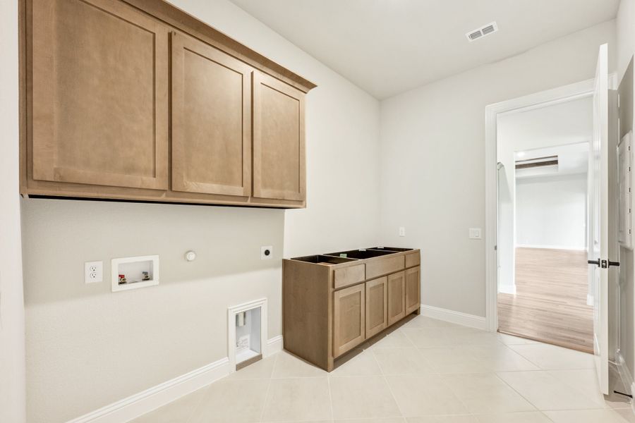 Laundry room with upper wood cabinets, base cabinet, washer and dryer hookups, and tile flooring Laundry room with upper wood cabinets, base cabinet, washer and dryer hookups, and tile flooring