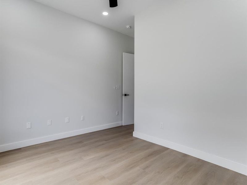 Downstairs guest bedroom. Light wood-finish flooring complements crisp white walls and baseboards Downstairs guest bedroom. Light wood-finish flooring complements crisp white walls and baseboards