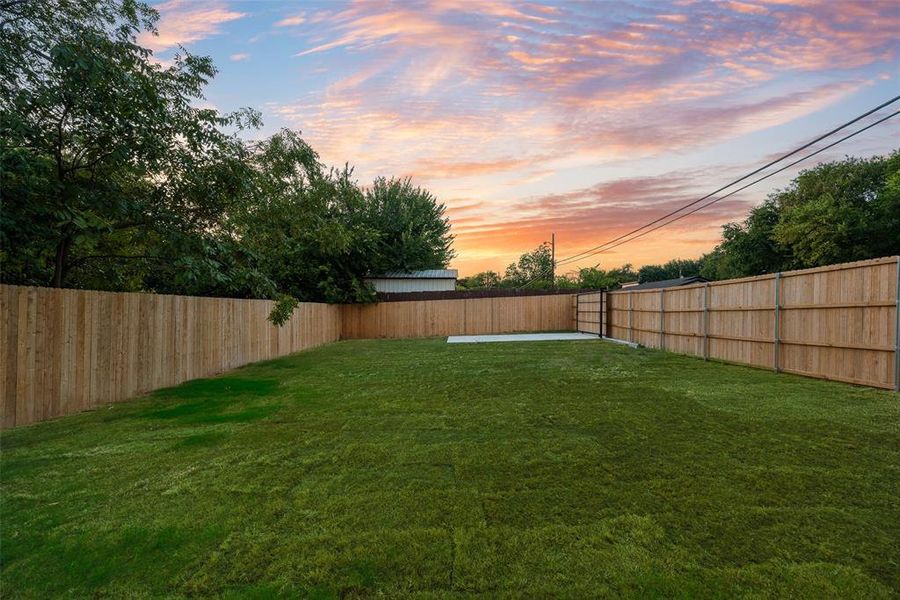 Yard at dusk with a fenced backyard and a patio