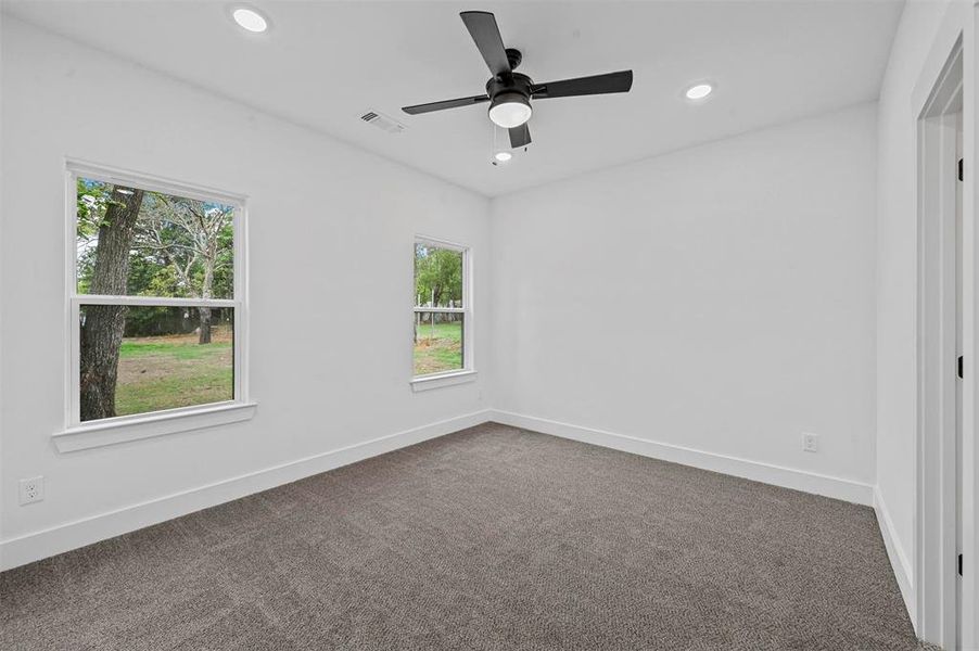 Spare room featuring ceiling fan, plenty of natural light, and carpet floors