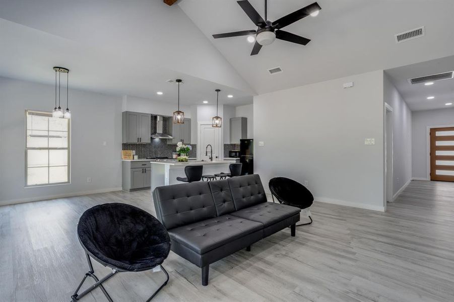 Living area with light wood finished floors, beam ceiling, ceiling fan, high vaulted ceiling, and recessed lighting Living area with light wood finished floors, beam ceiling, ceiling fan, high vaulted ceiling, and recessed lighting