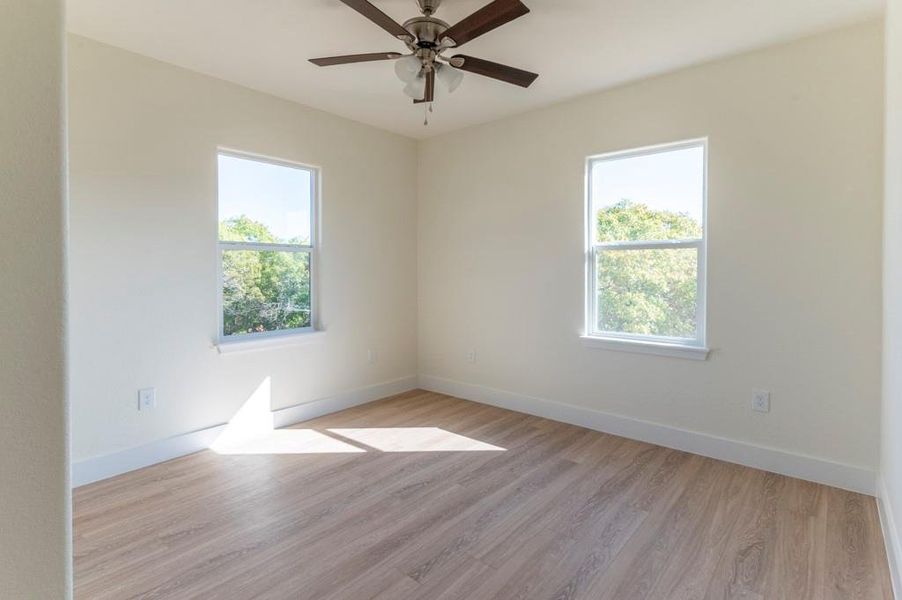 Empty room featuring light wood finished floors and ceiling fan