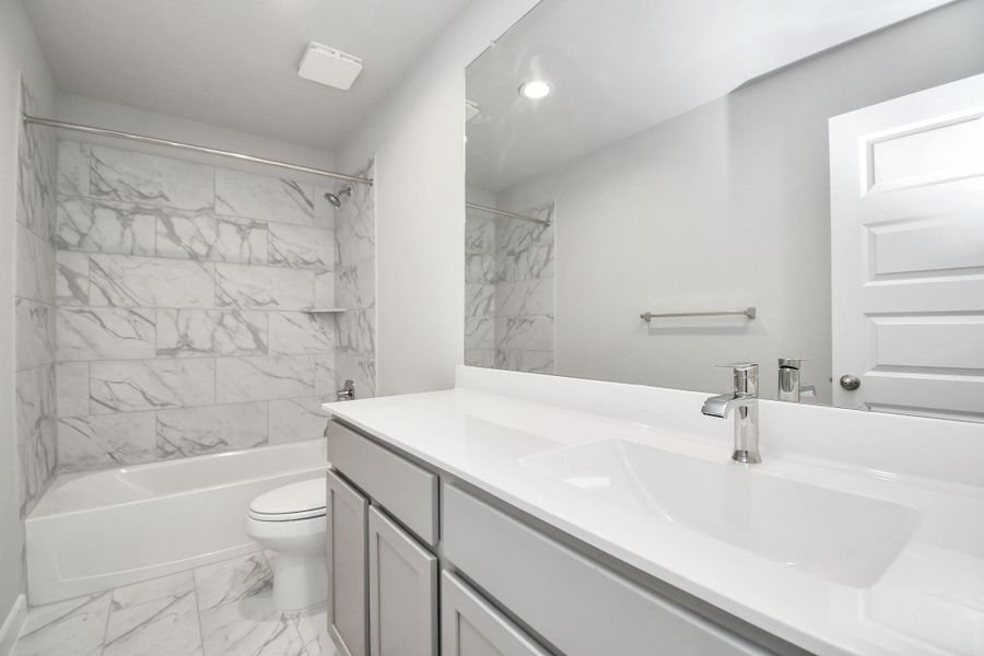 Secondary bath features tile flooring, bath/shower combo with tile surround, light stained wood cabinets, beautiful light countertop. Secondary bath features tile flooring, bath/shower combo with tile surround, light stained wood cabinets, beautiful light countertop.