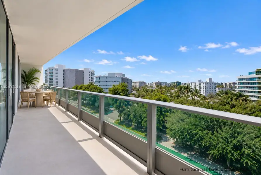 Covered balcony featuring a sleek glass railing with metal framing and concrete flooring Covered balcony featuring a sleek glass railing with metal framing and concrete flooring