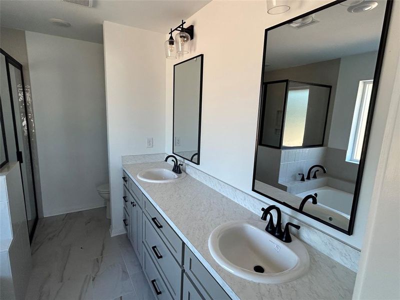 Full bathroom with double vanity, a garden tub, light marble finish floors, and a stall shower