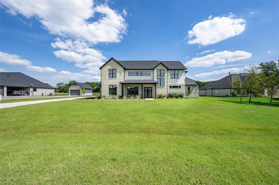View of front of property with stone siding, a front lawn, driveway, and a garage