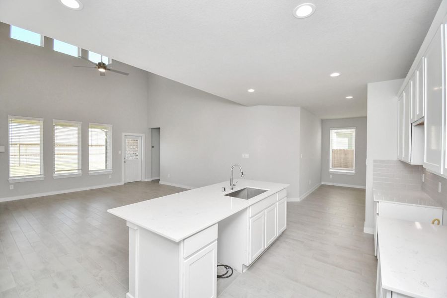 This generously spacious kitchen is a dream realized! With a massive granite island, high ceilings, soft close cabinets, granite countertops, stainless steel appliances, a sleek tile backsplash, recessed lighting, and an extended counter area, it offers both style and practicality. All this opens up to the expansive family room, creating a perfect hub for gatherings. Sample photo of completed home with similar floor plan. Actual colors and selections may vary.