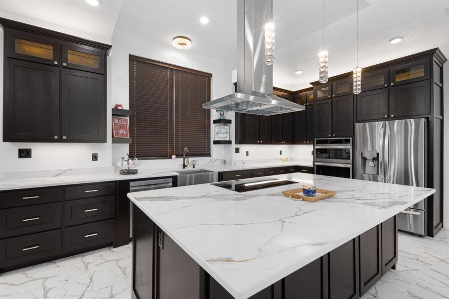 Kitchen with glass insert cabinets, light marble finish flooring, light stone counters, island range hood, and recessed lighting