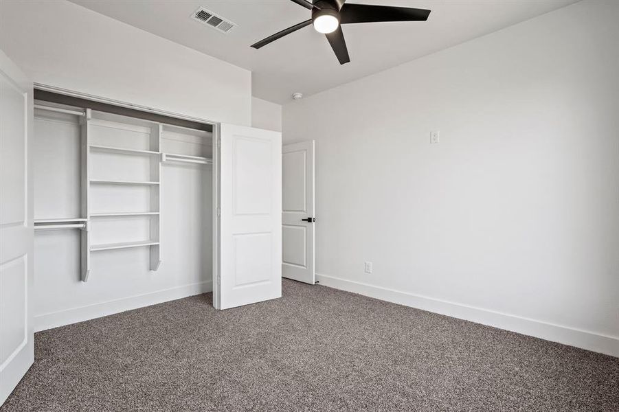 Unfurnished bedroom featuring ceiling fan, carpet, and a closet