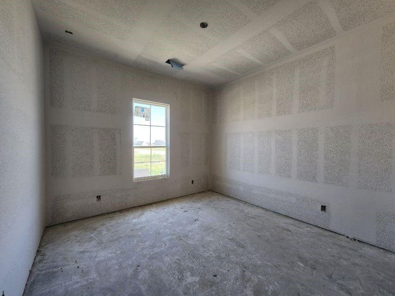 Room under construction featuring an untextured concrete floor, unfinished drywall walls, and a single-pane window with white framing