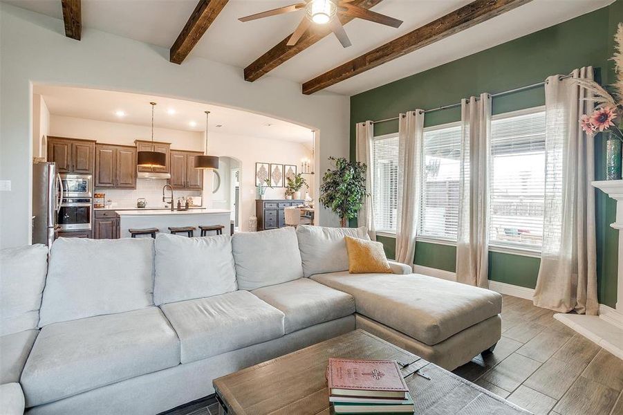 Living room with ceiling fan, beamed ceiling, and light wood-type flooring