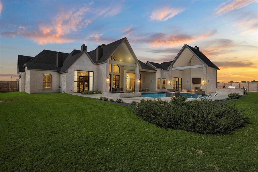 Back of property at dusk with a chimney and a patio