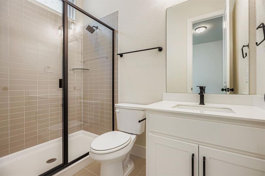 Full bathroom featuring vanity, a stall shower, tile patterned flooring, and a textured wall