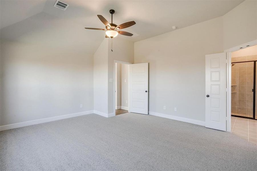 Unfurnished bedroom featuring ensuite bath, ceiling fan, high vaulted ceiling, and light carpet