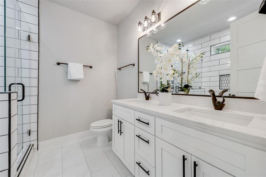 Bathroom with vanity, a shower with shower door, and toilet