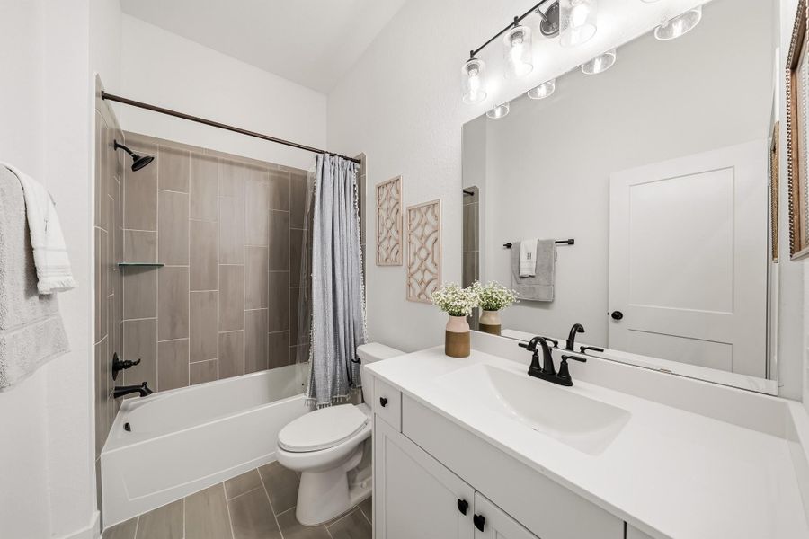 The third bathroom is thoughtfully appointed with tile flooring, a sleek quartz countertop, and a decorative light fixture that adds an elevated touch to this stylish and functional space.