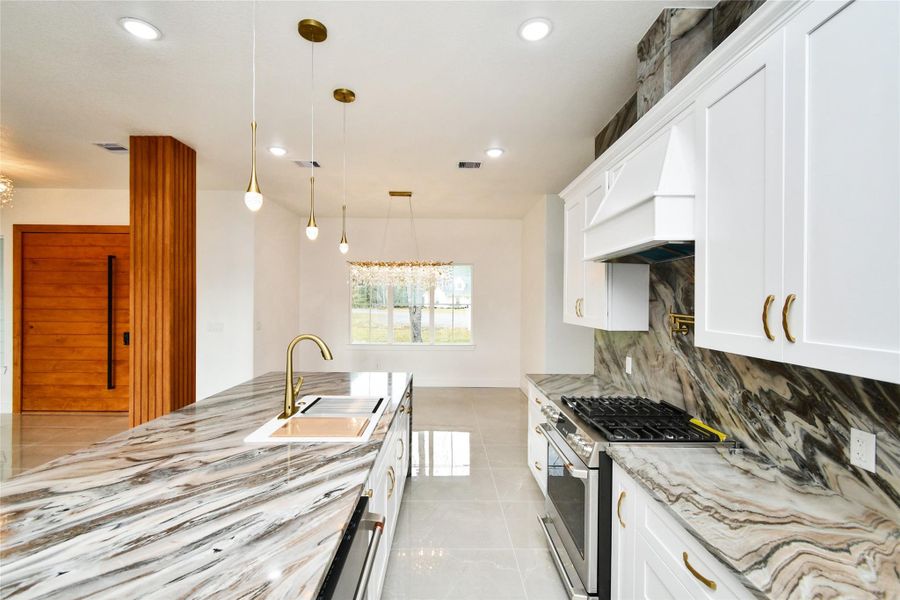 A chef's perspective of the gourmet kitchen, highlighting the functional layout, high-end gold-tone hardware, and designer pendant lighting that creates a warm, sophisticated ambiance.
