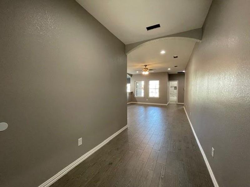 Hallway with arched walkway, ceramic wood-style finished floors, and baseboards Hallway with arched walkway, ceramic wood-style finished floors, and baseboards