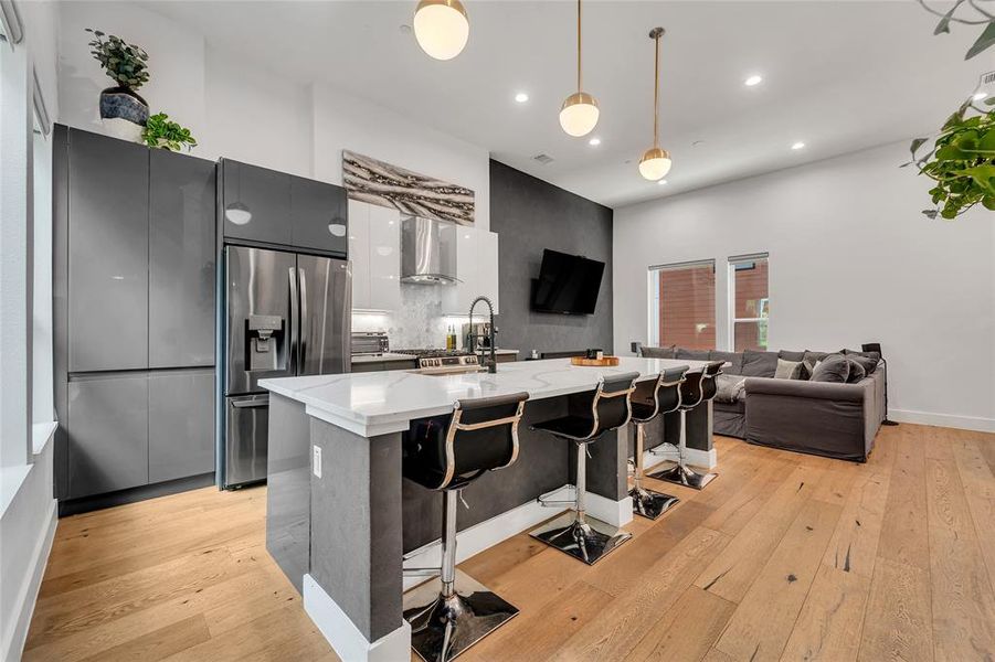 Kitchen with modern cabinets, a breakfast bar area, hanging light fixtures, light wood-type flooring, and recessed lighting Kitchen with modern cabinets, a breakfast bar area, hanging light fixtures, light wood-type flooring, and recessed lighting