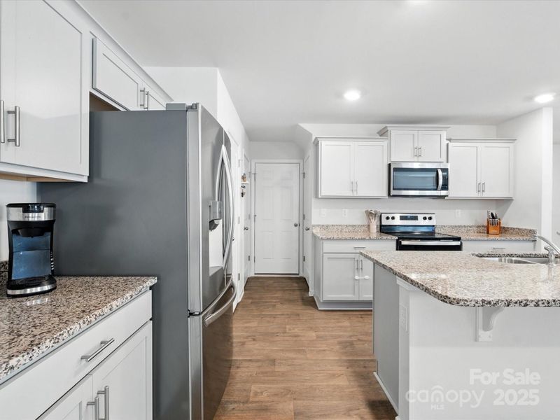Well-appointed kitchen with convenient pantry access and abundant counter space. Stainless appliances and granite surfaces provide modern functionality in this thoughtfully designed cooking space.