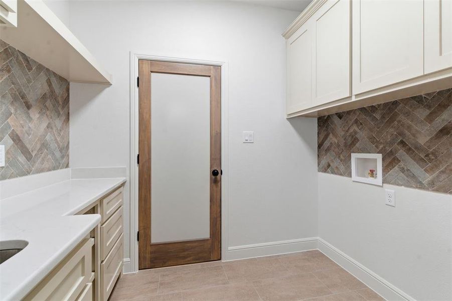 Laundry room with light tile patterned floors, washer hookup, and cabinet space Laundry room with light tile patterned floors, washer hookup, and cabinet space