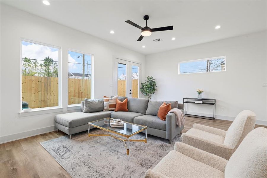 A bright, airy living room featuring high ceilings, large windows for natural light, and elegant recessed lighting.