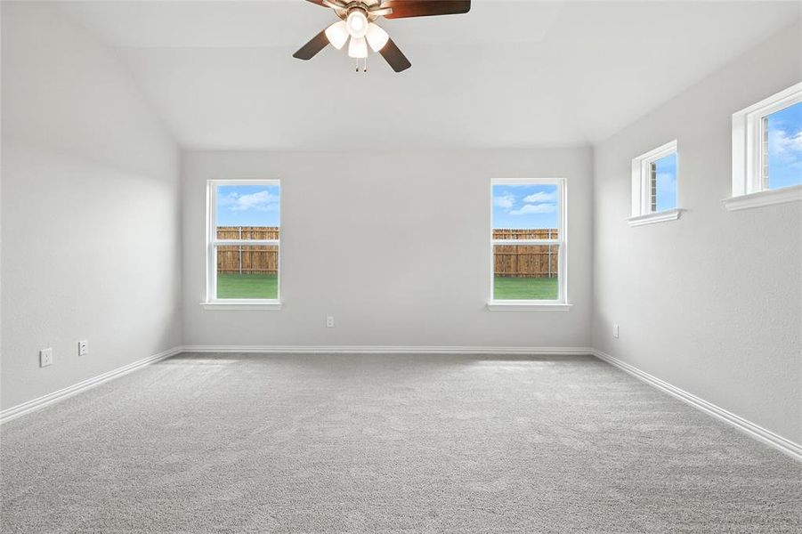 Empty room with lofted ceiling, a ceiling fan, and carpet flooring