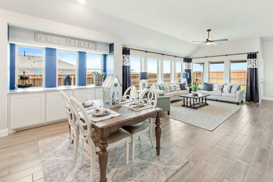 Open-concept dining and living area with vaulted ceiling, wood-look tile floors, and large windows