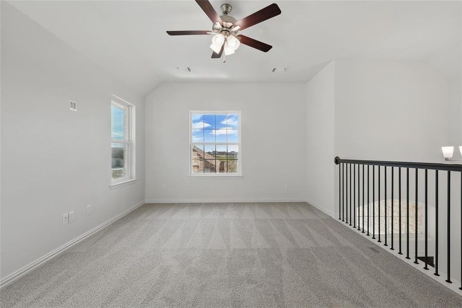 Unfurnished room with vaulted ceiling, light colored carpet, a ceiling fan, and baseboards Unfurnished room with vaulted ceiling, light colored carpet, a ceiling fan, and baseboards