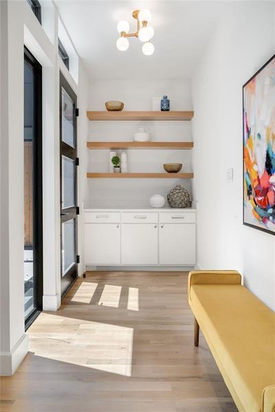 Hallway featuring light hardwood / wood-style floors and a notable chandelier