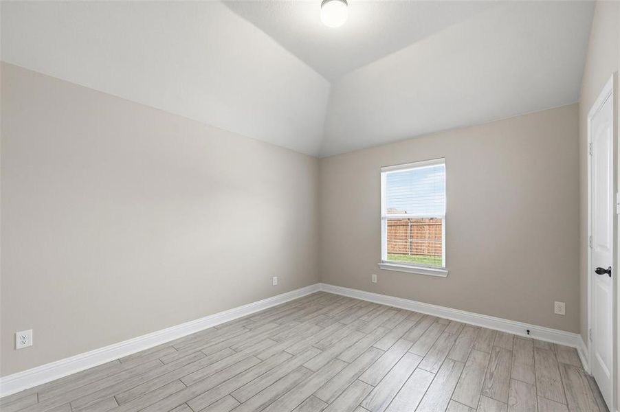 Spare room featuring wood tiled floors and vaulted ceiling Spare room featuring wood tiled floors and vaulted ceiling