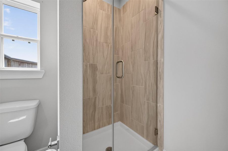 Stylish and efficient, the bathroom includes a frameless glass shower with warm tile surround and contemporary fixtures. Perfect for guests or daily use with its timeless design and thoughtful layout.