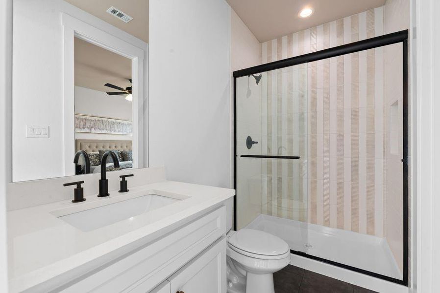 Full bath featuring vanity, a stall shower, dark tile patterned floors, and ceiling fan Full bath featuring vanity, a stall shower, dark tile patterned floors, and ceiling fan
