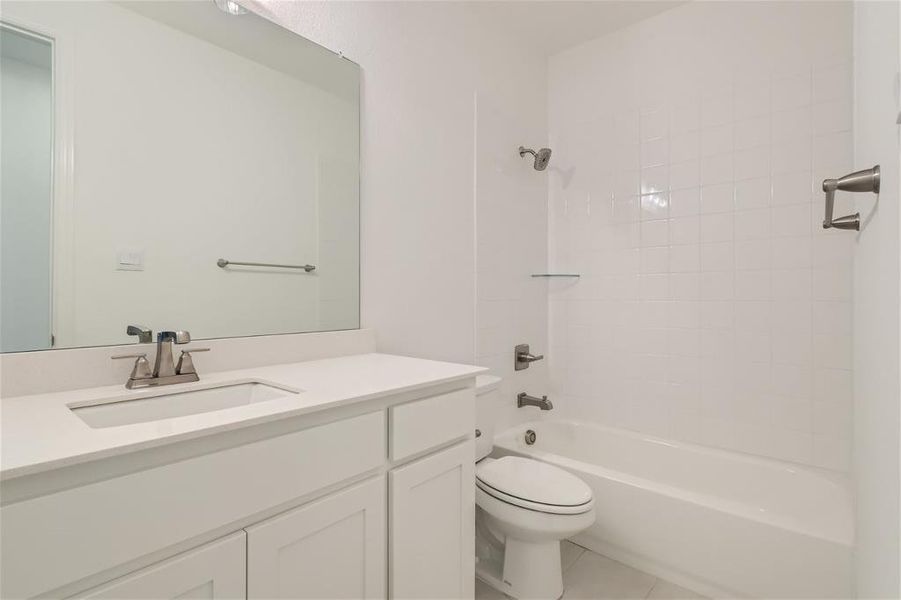 Full bathroom with tile floors, tiled shower / bath, oversized vanity, and toilet