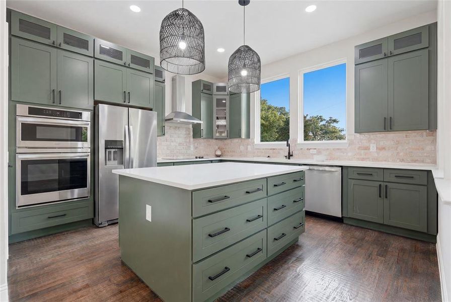 Modern kitchen featuring a large central island with a white countertop and olive green cabinetry Modern kitchen featuring a large central island with a white countertop and olive green cabinetry