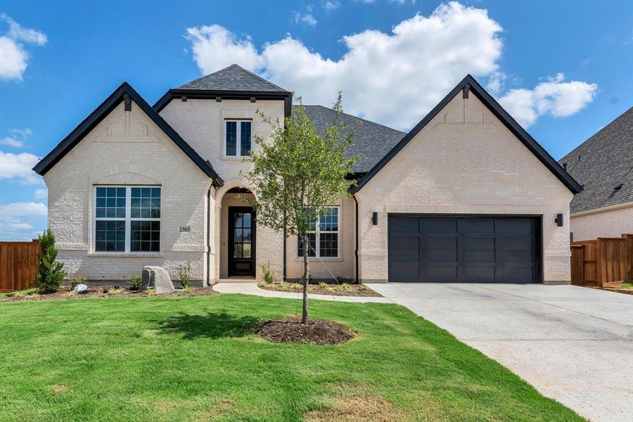 French country style house with a garage and a front lawn